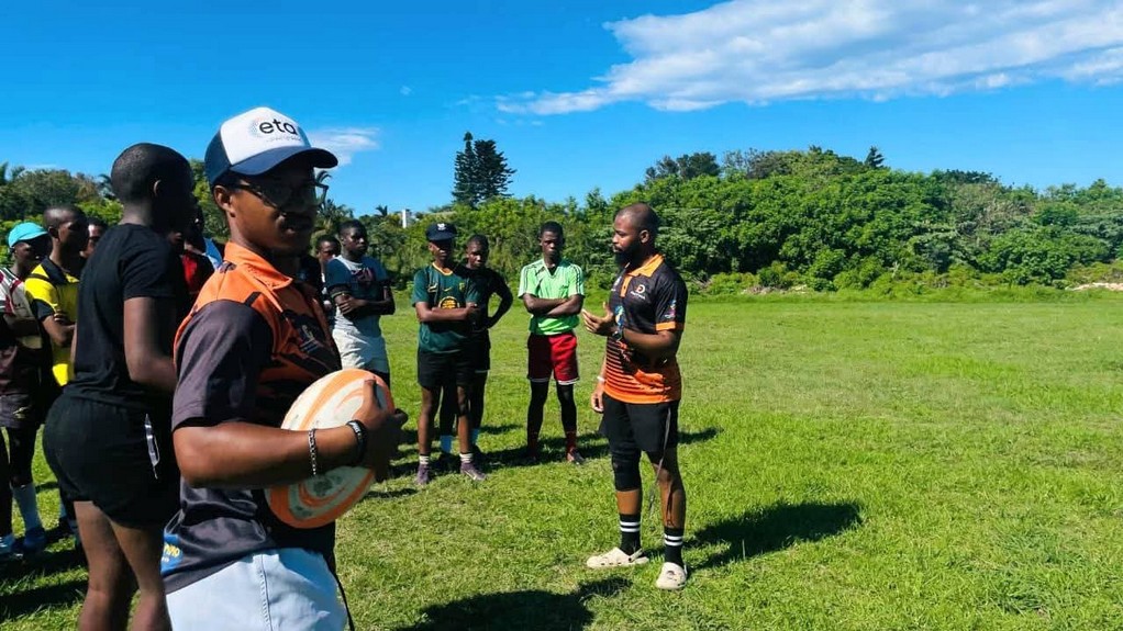 Coach speaking to young players in a huddle on the field